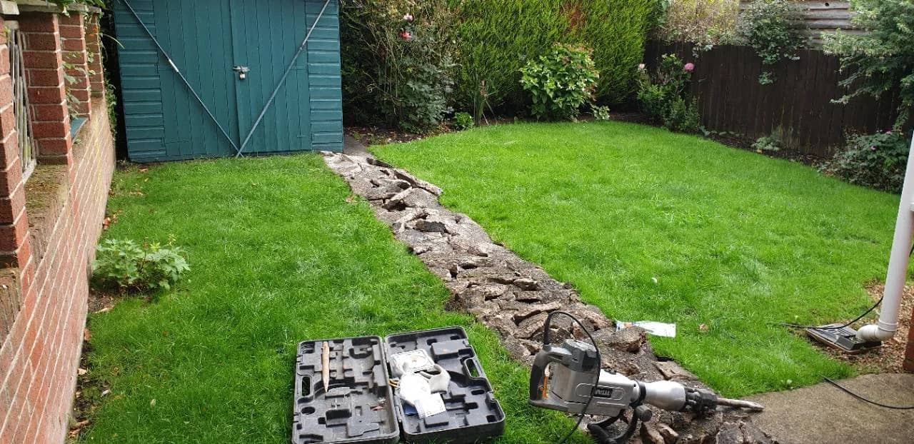 Before photo of a Bridgwater garden with lawn and old broken path before resin patio and artificial grass installation