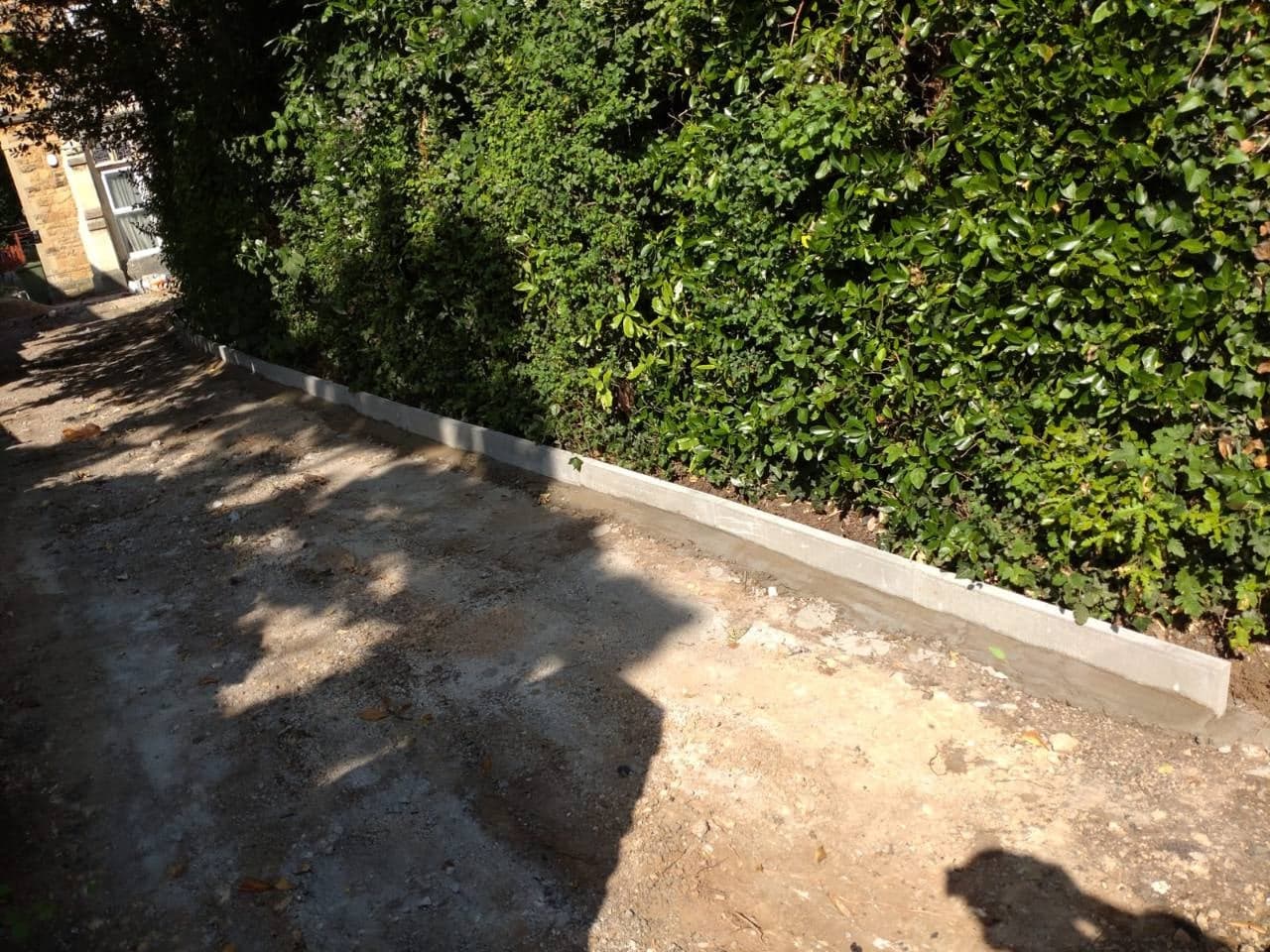 Side driveway kerb edging set beside the boundary hedge in Weston-super-Mare
