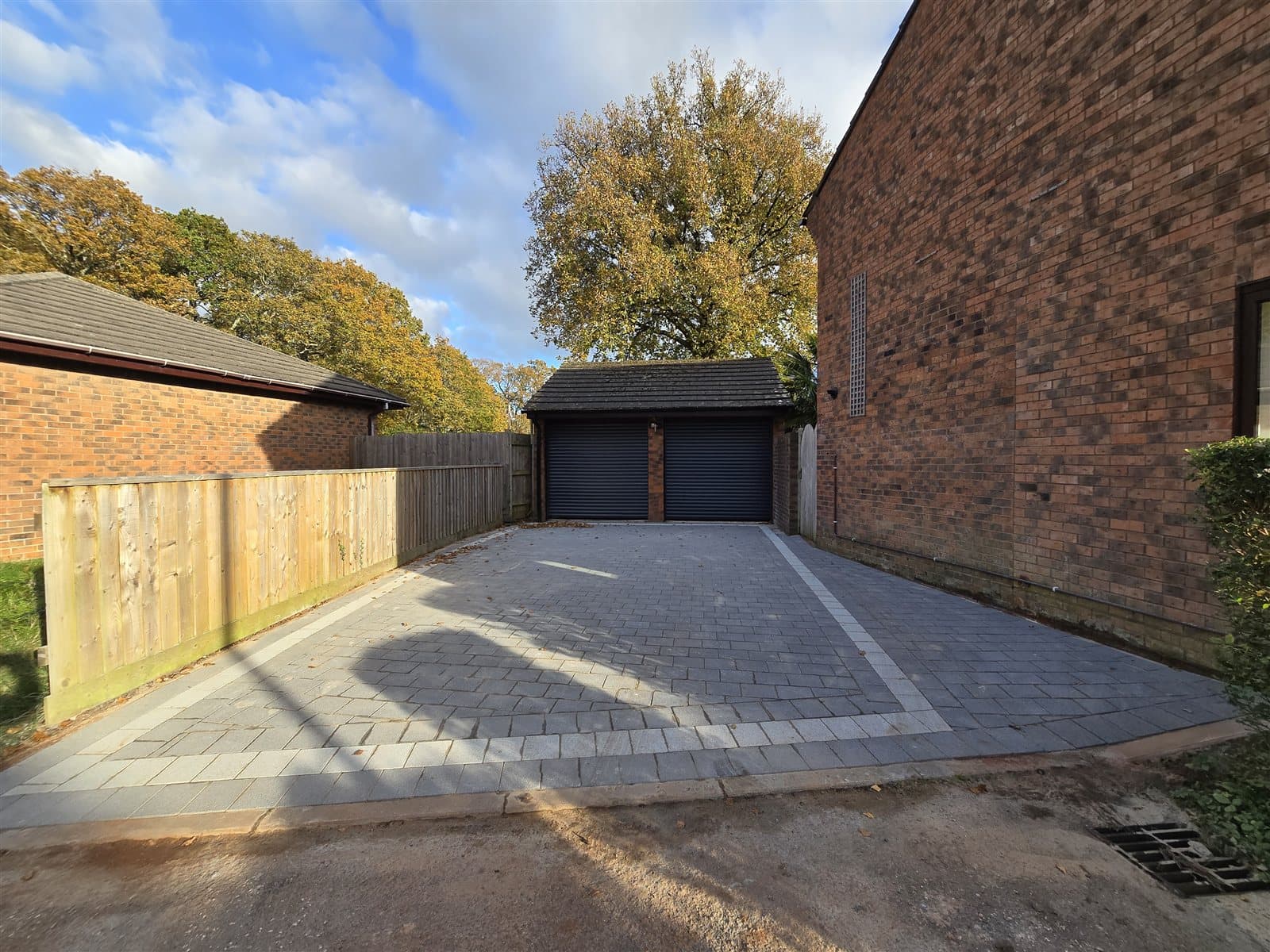 Grey block paving driveway with light border to a double garage