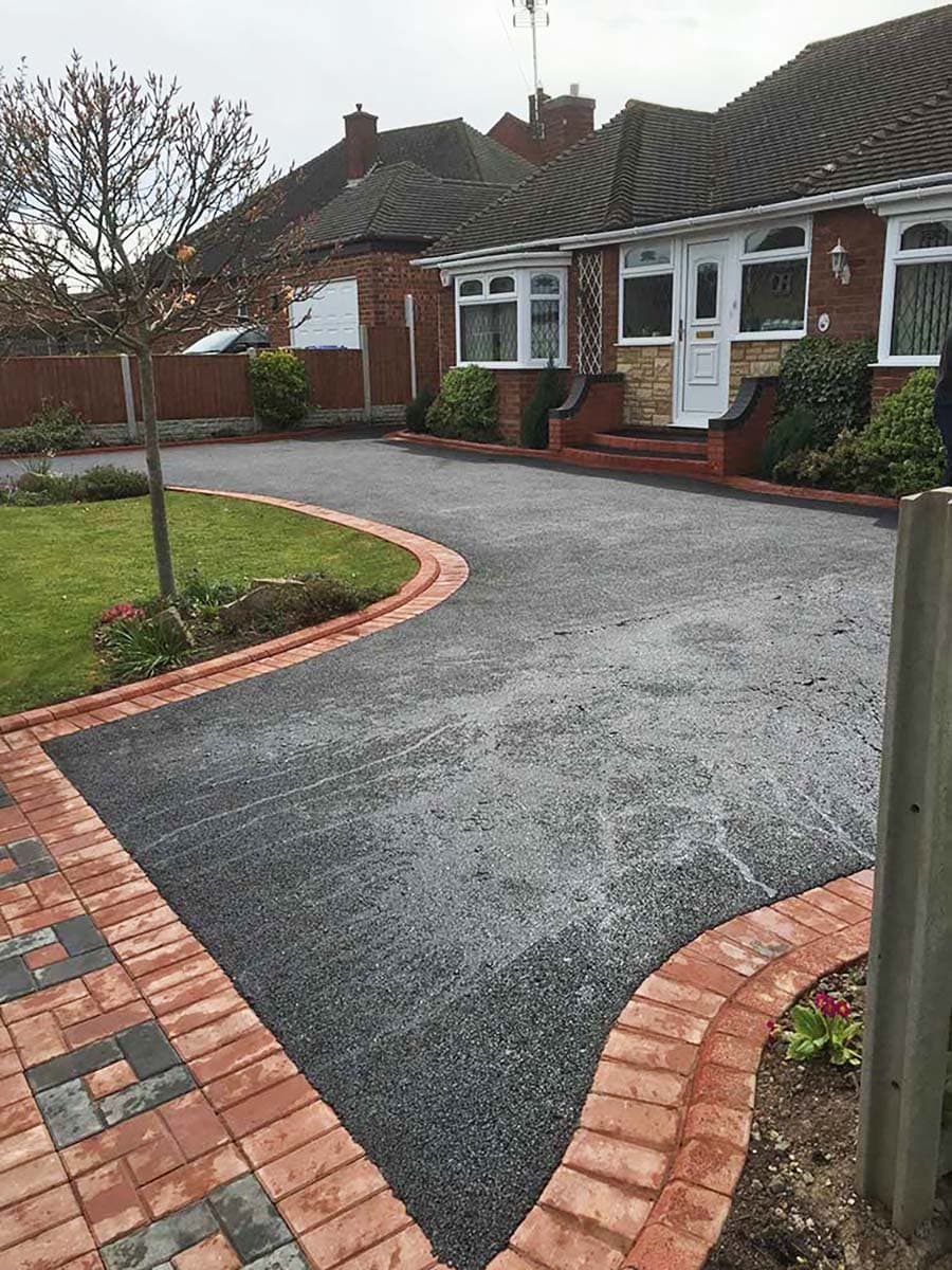 Tarmac driveway with red block paved border and curved beds