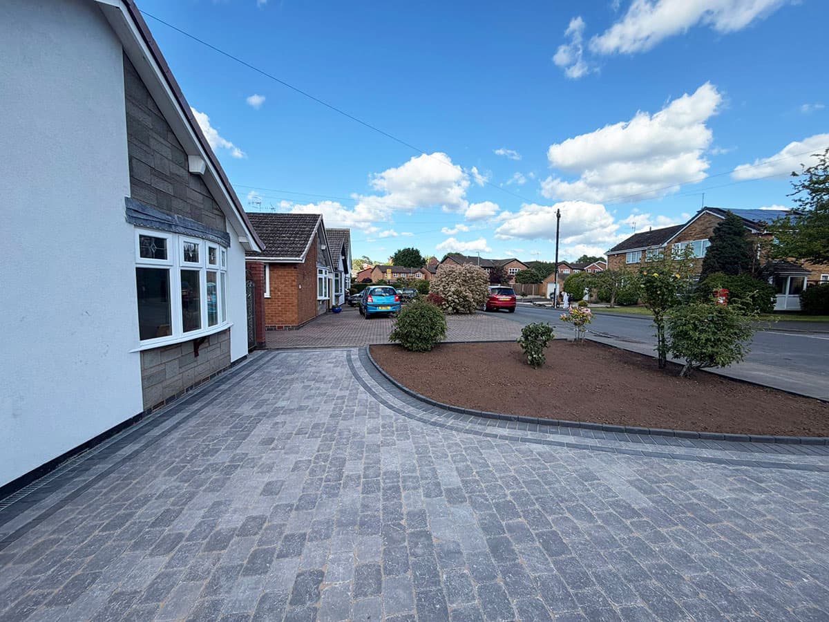 Grey cobble-style block paving driveway with planting beds
