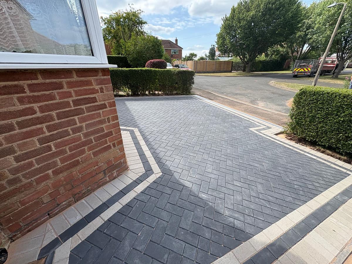 Charcoal herringbone block paving wrapping the front corner