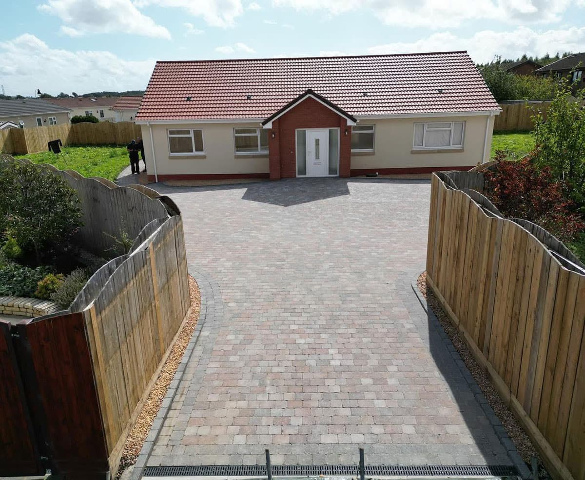 Sweeping rustic block paved driveway with drainage channel