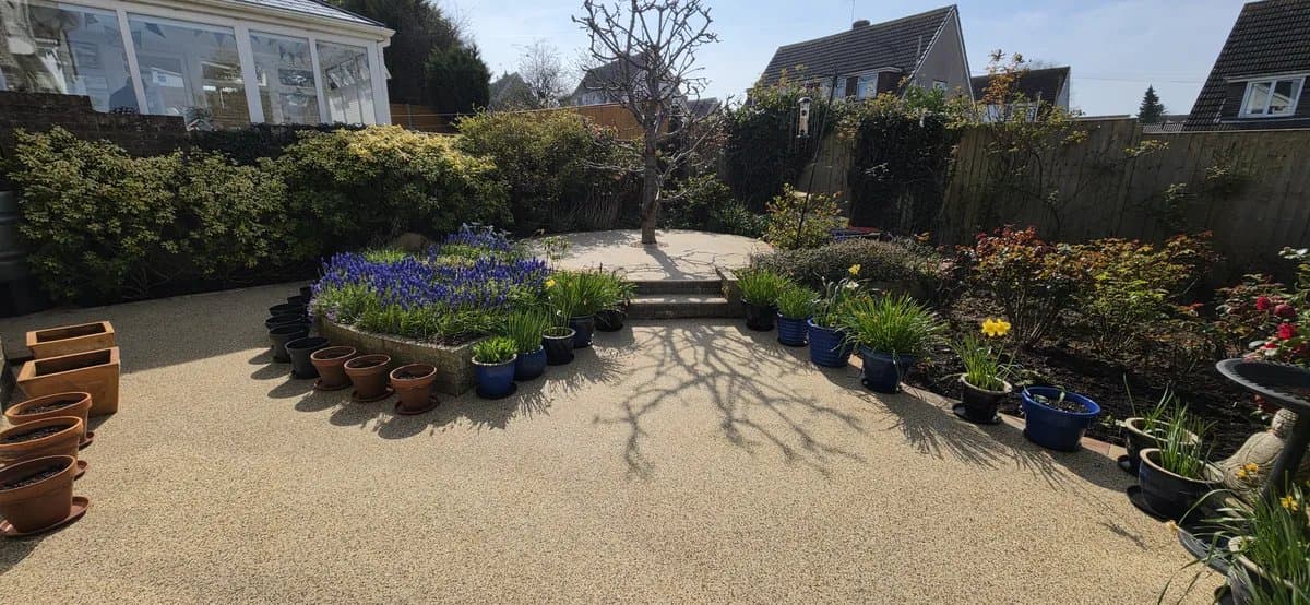 Golden resin bound garden patio with raised planted beds and steps
